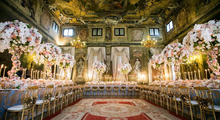 The frescoed Sala della Musica dressed for a wedding, floral arches above the banquet tables beneath the painted ceiling, Ca' Sagredo Hotel