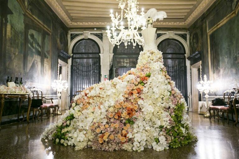 A cascade of flowers beneath a chandelier in a painted salon, dressed for the ceremony, Ca' Sagredo Hotel