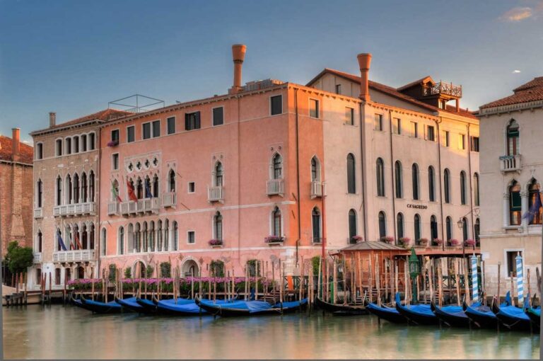 Ca' Sagredo, its rose-pink 15th-century Gothic facade rising from the Grand Canal above the gondolas, Ca' Sagredo Hotel