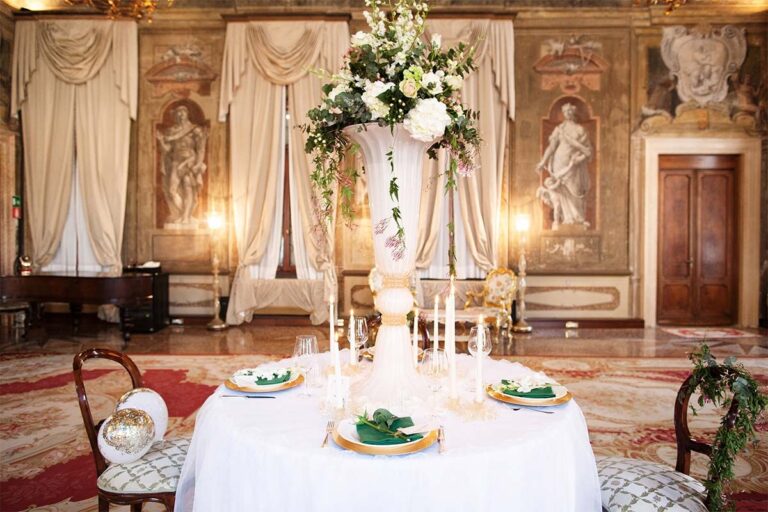 A sweetheart table crowned with a towering floral arrangement in a frescoed hall, Ca' Sagredo Hotel