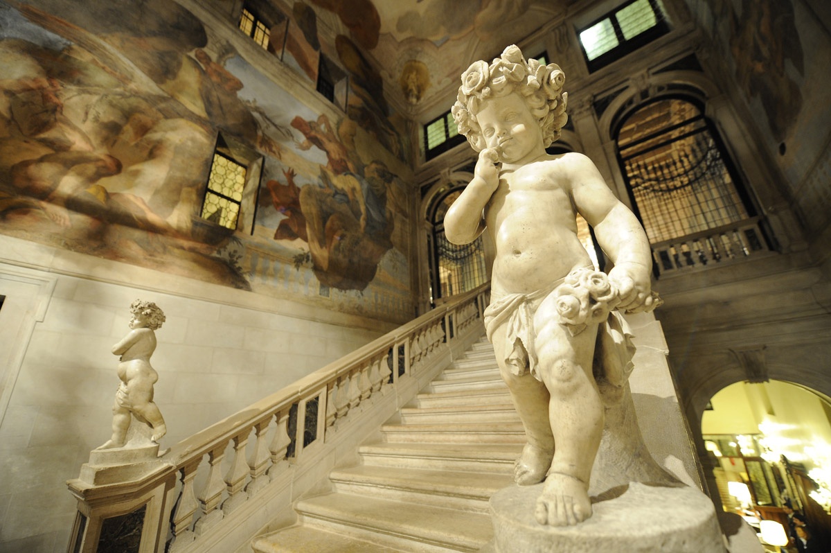 The monumental staircase by Andrea Tirali, sculpted figures on the balustrade beneath a fresco, Ca' Sagredo Hotel
