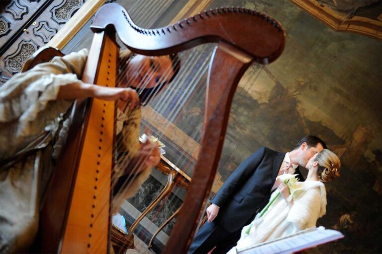 A harpist plays as a couple embrace in a frescoed salon of the palazzo, Ca' Sagredo Hotel