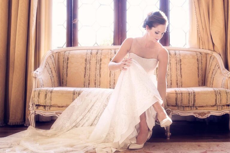 A bride fastens her shoe on a sofa in a light-filled salon, Ca' Sagredo Hotel