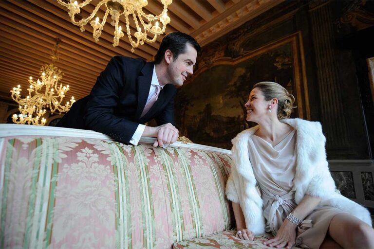 A couple on a damask sofa in a painted salon, the bride in white fur, Ca' Sagredo Hotel