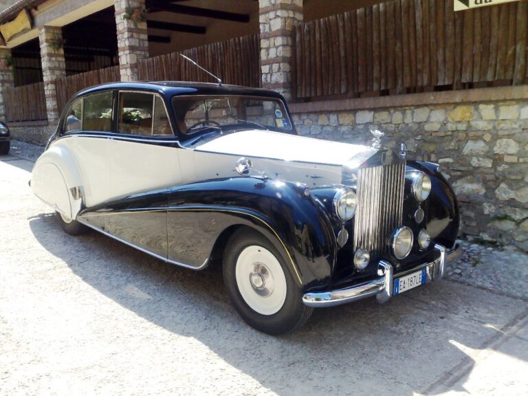 Black and white Rolls-Royce from 1950 beside a stone wall, Canestri Autonoleggi, Car Hire Italy