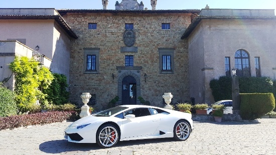 White Lamborghini Huracan at the entrance of a stone villa, Canestri Autonoleggi, Car Hire Italy