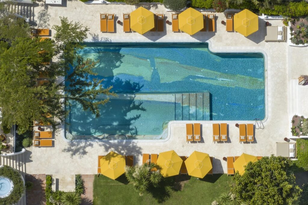 The outdoor pool and yellow parasols seen from above, Capri Palace Jumeirah