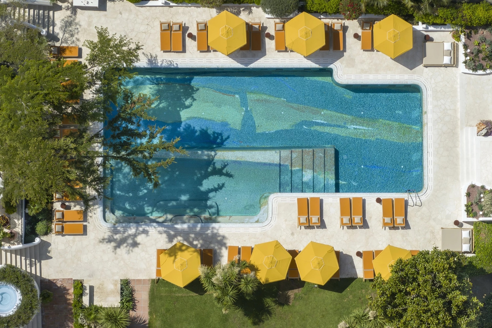 The outdoor pool and yellow parasols seen from above, Capri Palace Jumeirah