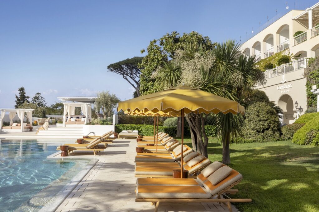 Pool terrace with sun loungers and a yellow parasol beside the hotel, Capri Palace Jumeirah