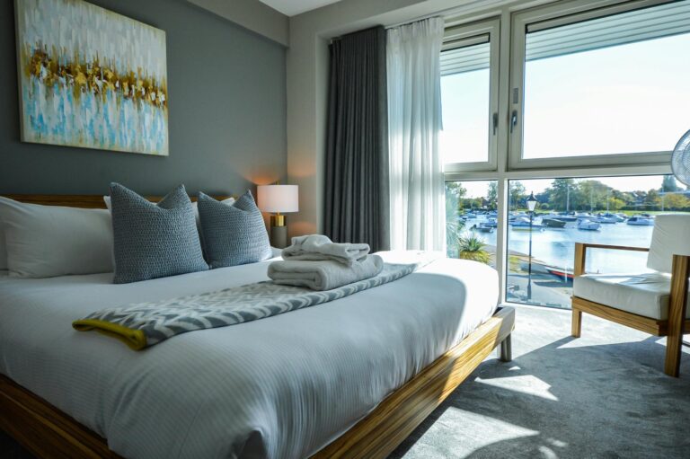 A double stateroom with a large bed and floor-to-ceiling windows over the river and moored boats, Captain's Club Hotel & Spa