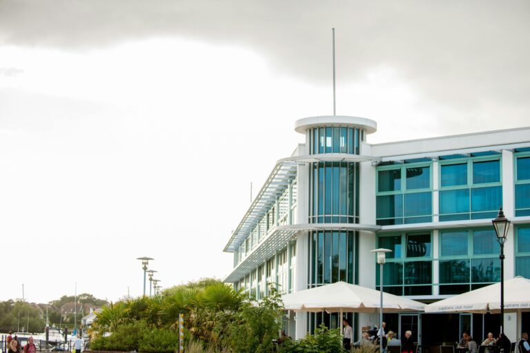 The hotel's round glazed stair tower and ship-like white and glass facade, seen from the quayside with the terrace parasols below, Captain's Club Hotel & Spa