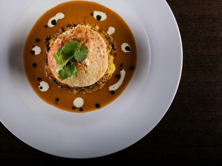 A golden-crusted cake on a spiced sauce dotted with yoghurt, garnished with coriander, Captain's Club Hotel & Spa