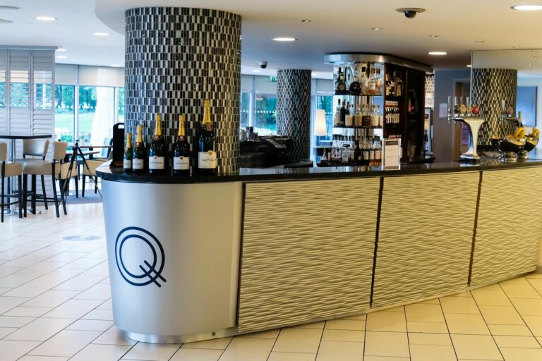 The curved Quay Bar counter with its Q logo, tiled columns and wine bottles on display, Captain's Club Hotel & Spa