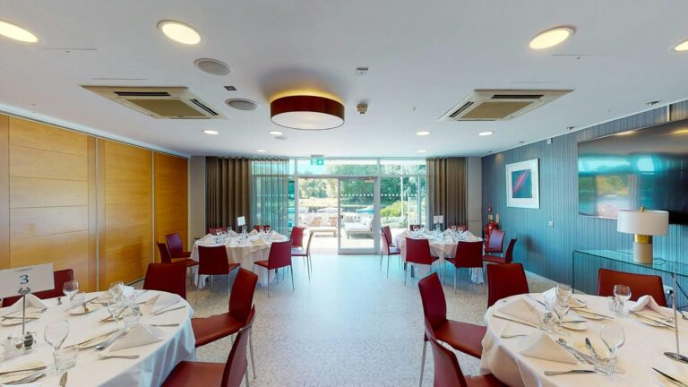 The Port Suite set with round tables and red chairs, glass doors at the far end opening towards the terrace, Captain's Club Hotel & Spa