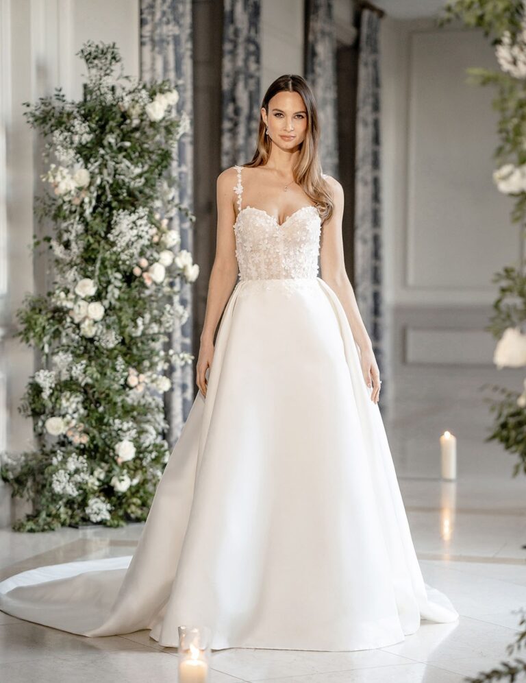 The Kira gown from the Icon collection among white floral arrangements, Caroline Castigliano