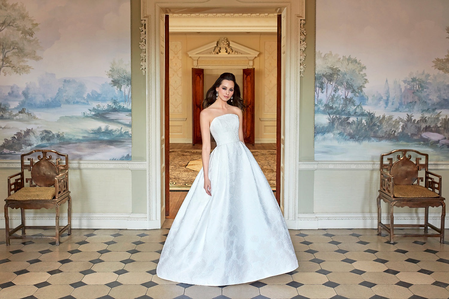 The Magnolia gown in a panelled doorway with a painted mural, Caroline Castigliano