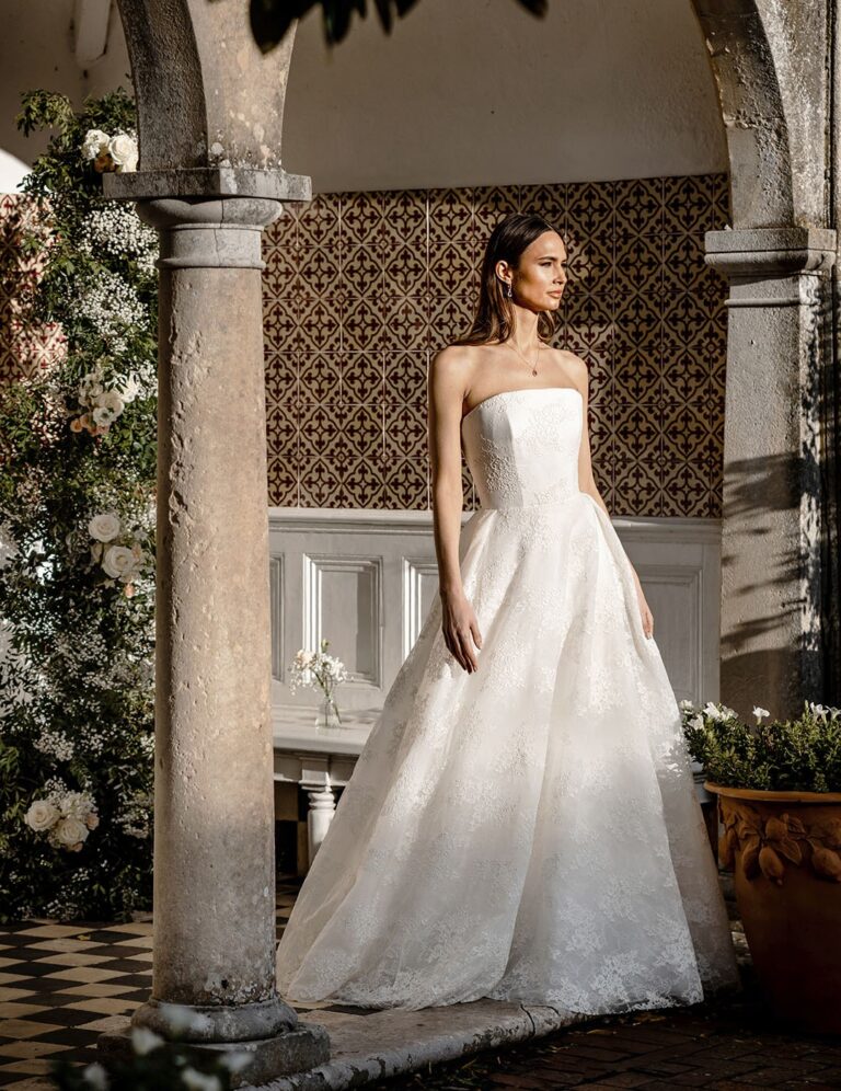 The Stephanie gown from the Icon collection in a tiled stone arcade, Caroline Castigliano