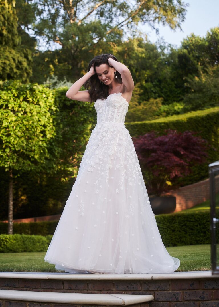 The Liberty gown with floral appliqué in a landscaped garden, Celebration collection, Caroline Castigliano