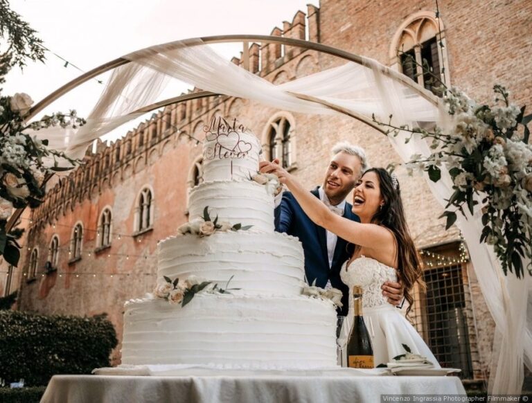 The bride and groom at the wedding cake, castle courtyard, Castello Bevilacqua
