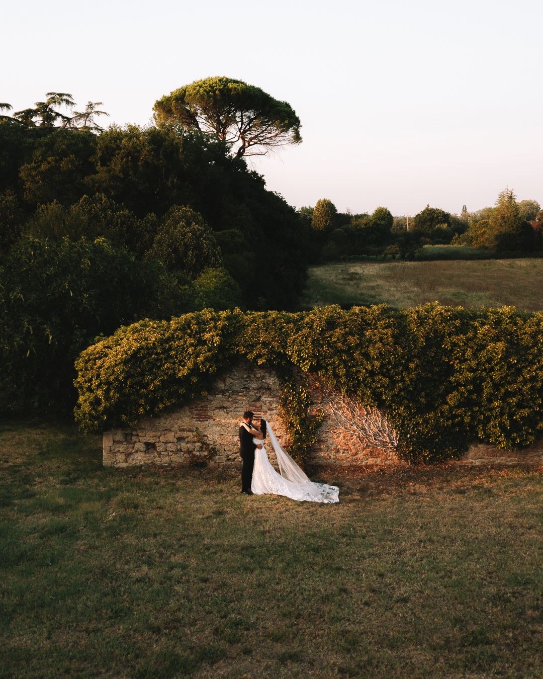 A couple on the lawn beside a clipped hedge at dusk, Castello del Capitano delle Artiglierie