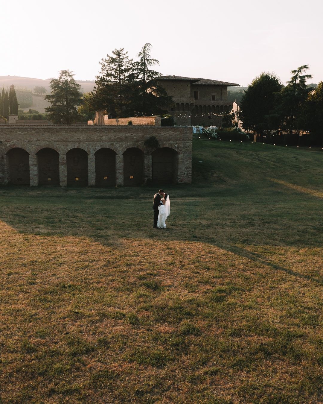 A couple on the lawn in front of a brick arcade, Castello del Capitano delle Artiglierie