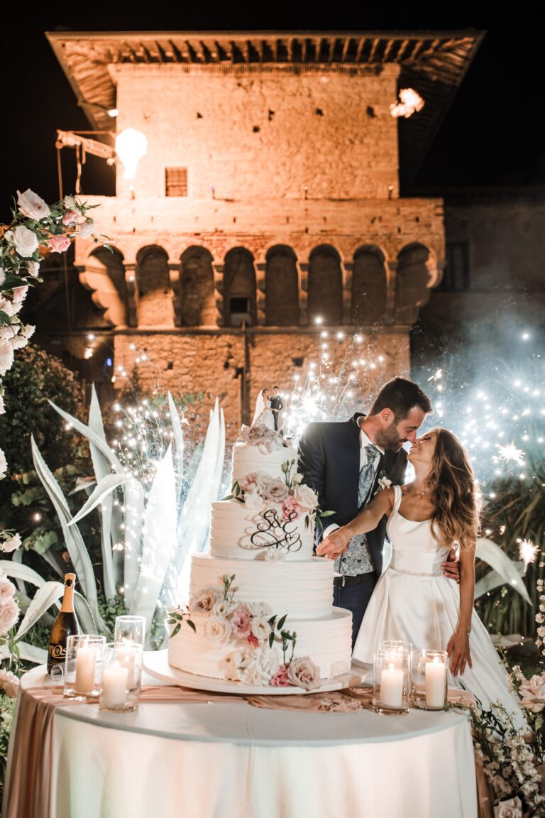 A couple cutting the wedding cake in front of the castle tower, with sparklers, Castello del Capitano delle Artiglierie