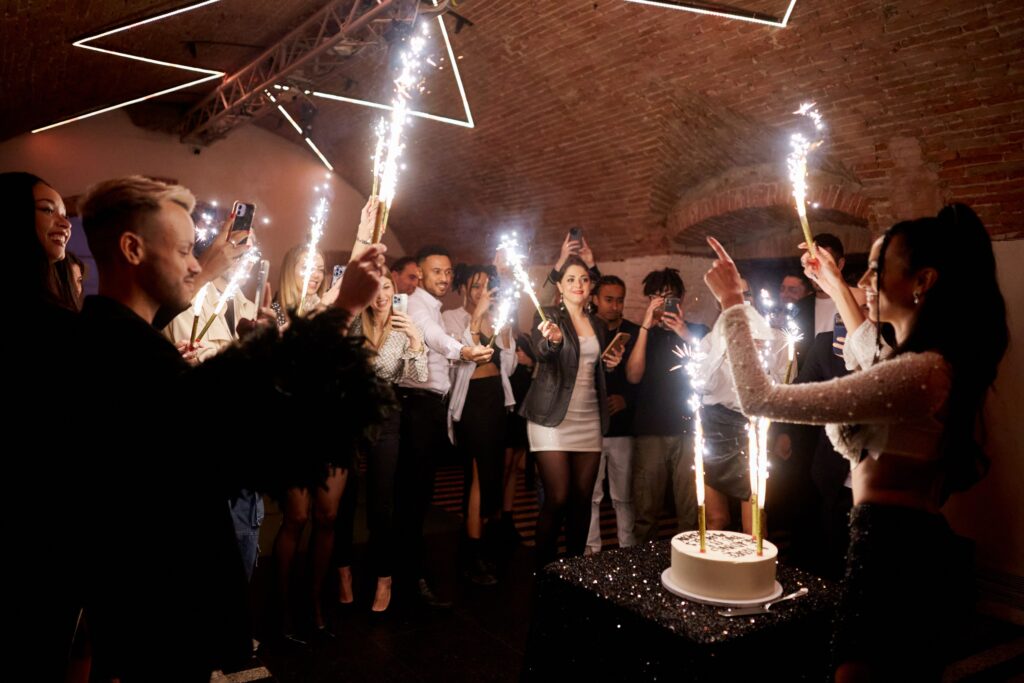 Guests holding sparklers around a cake in a vaulted room, Castello del Capitano delle Artiglierie