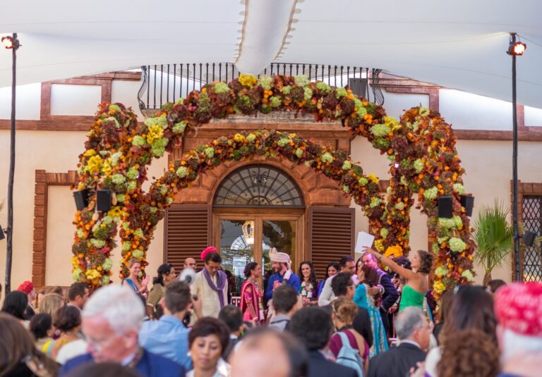 Ceremony beneath an autumnal floral arch at the castle entrance, Castello di Solfagnano