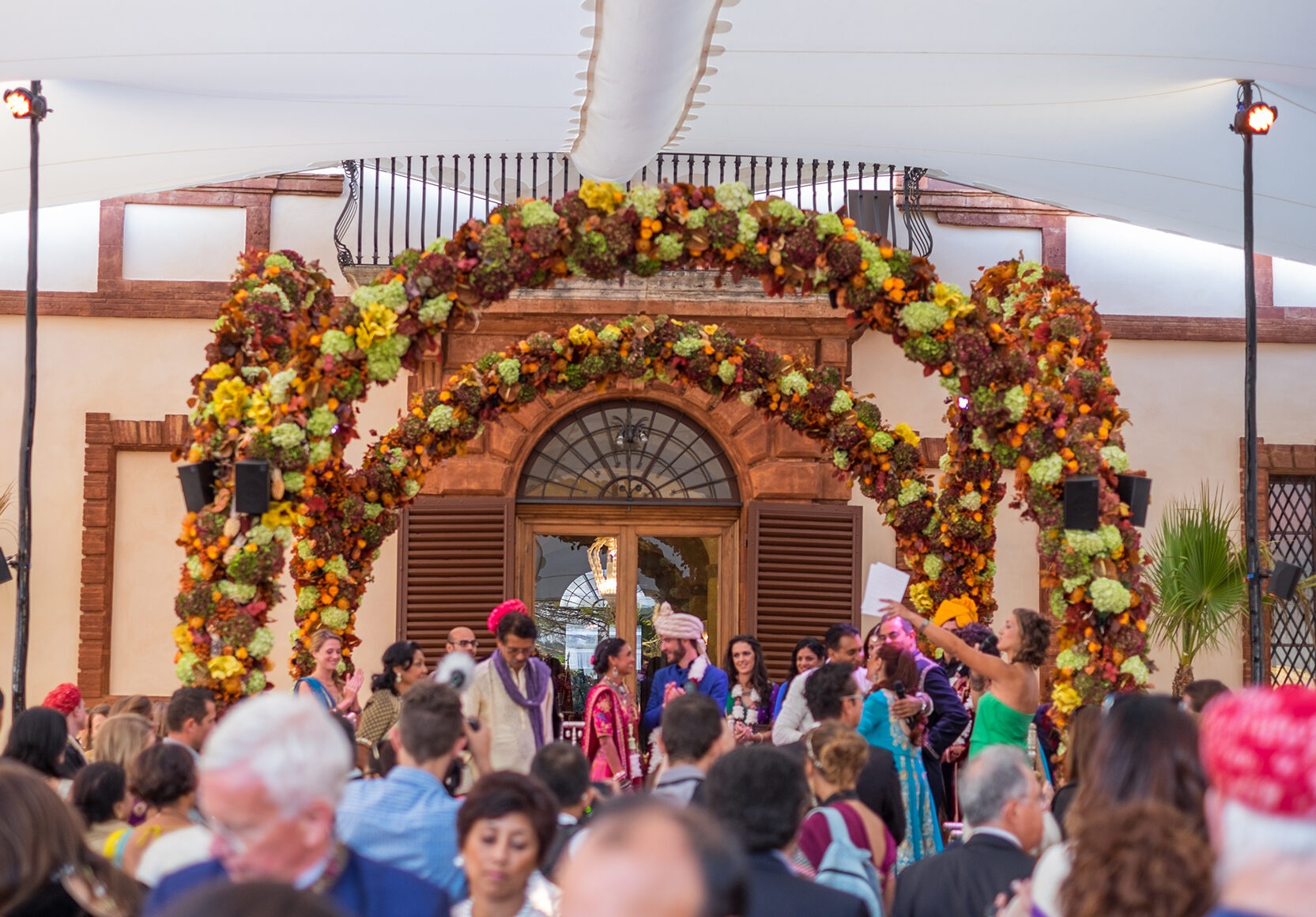 Ceremony beneath an autumnal floral arch at the castle entrance, Castello di Solfagnano