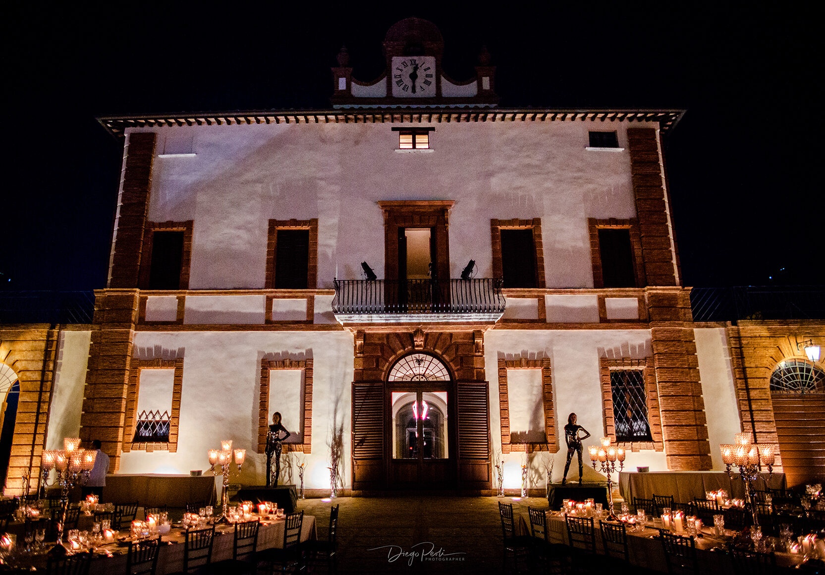 Castle facade lit at night, candlelit reception tables on the terrace, Castello di Solfagnano