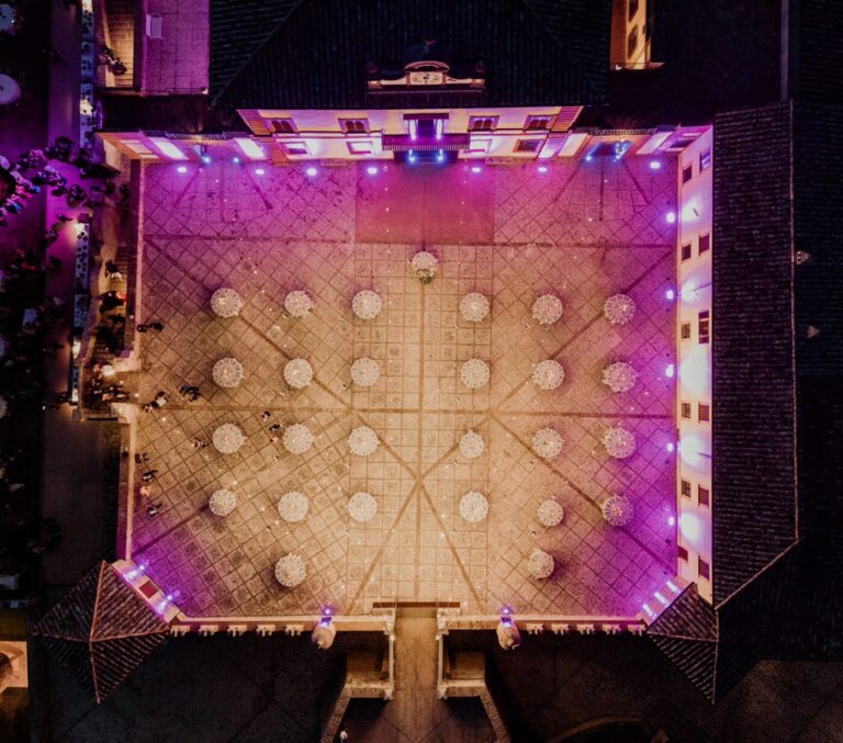 Aerial of the castle courtyard with fountain, tables set for the reception, Castello di Solfagnano