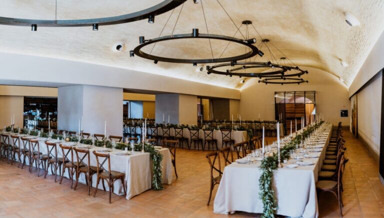 The vaulted stone dining hall, long tables dressed with greenery garlands, Castello di Solfagnano