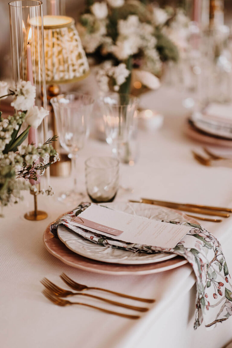 A place setting with gold cutlery, a pink charger and a patterned napkin, Caswell House