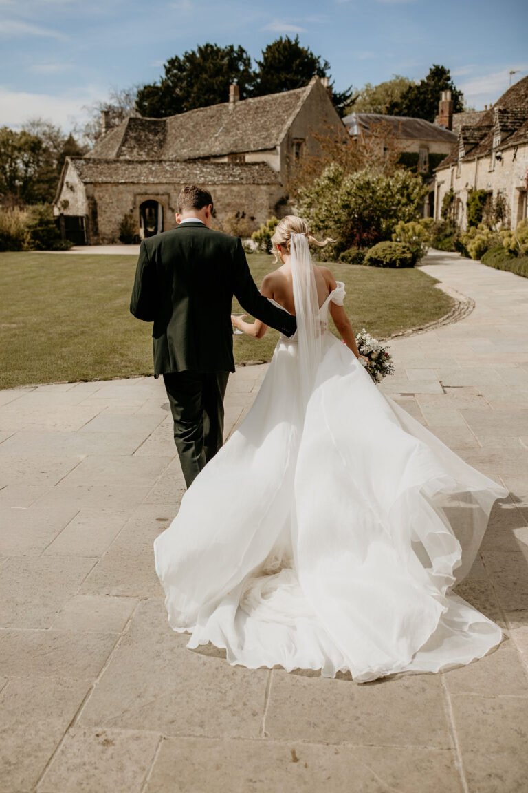 A couple walking along the garden path towards the house and barns, Caswell House