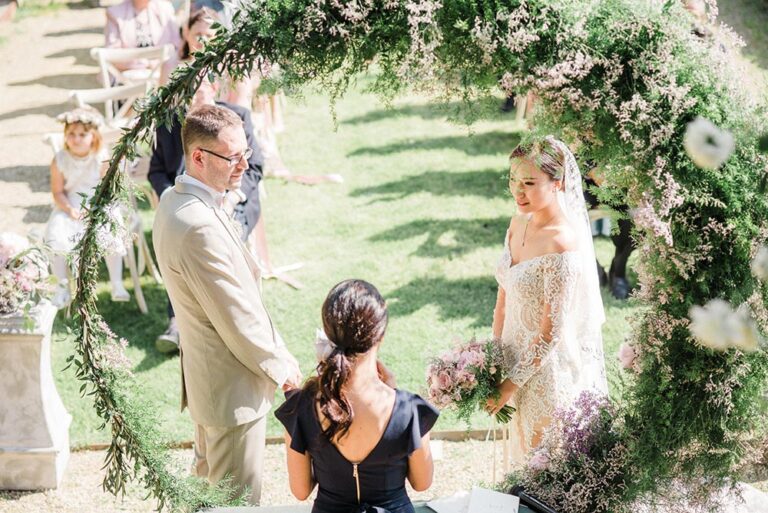 Ceremony beneath a floral ring in a garden, Caterina Weddings