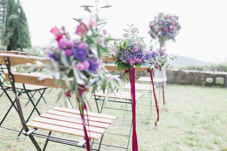 Aisle chairs with purple and burgundy floral arrangements, Caterina Weddings