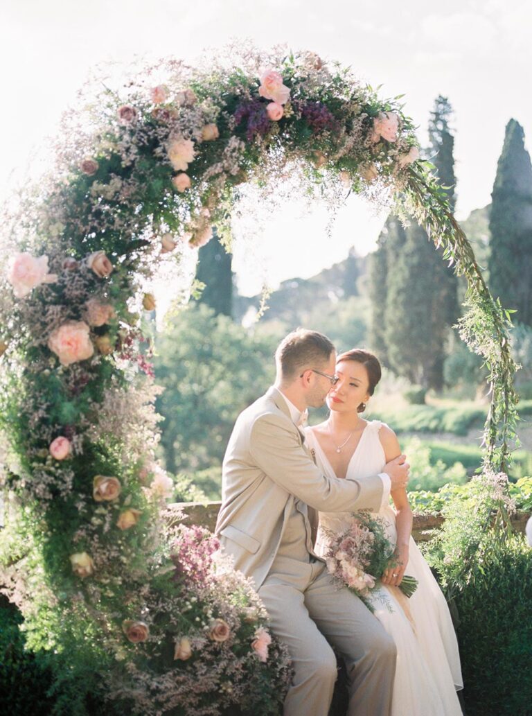 The couple seated within a floral arch overlooking Florence, Caterina Weddings