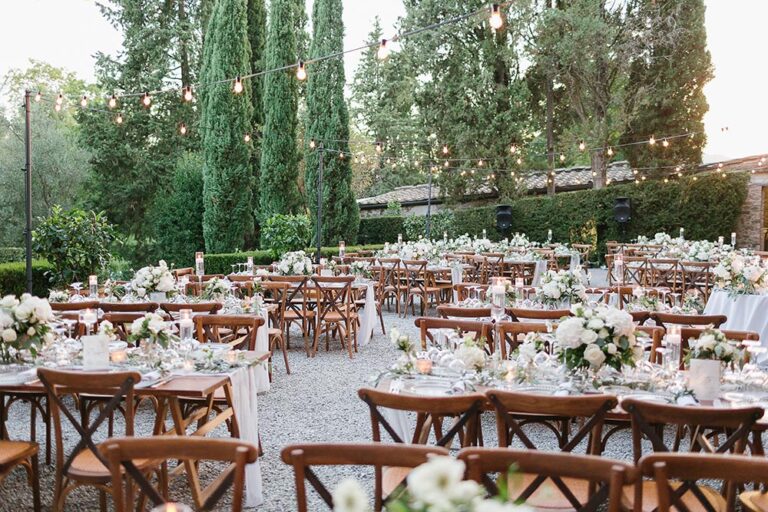 Long wooden tables laid for dinner in a villa garden, Caterina Weddings