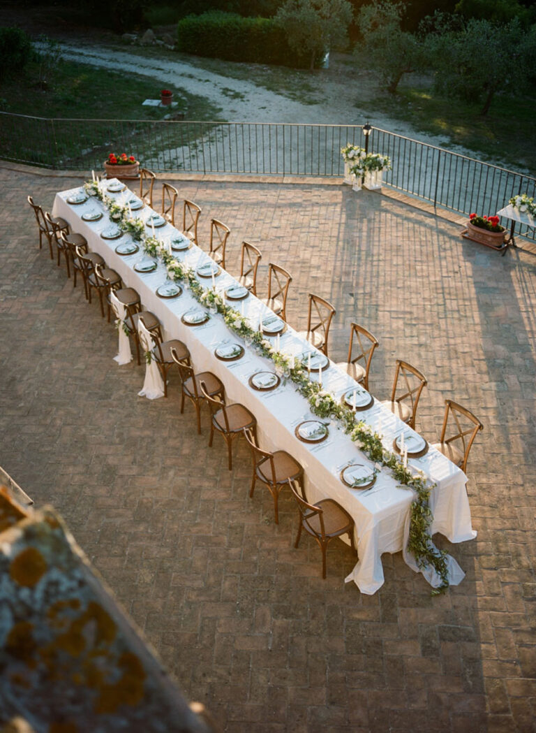 Aerial view of a long banquet table in an olive-lined courtyard, Caterina Weddings