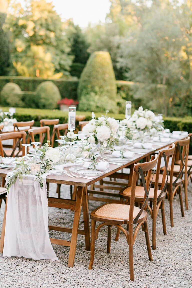 Dinner table with greenery runner and wooden chairs, Caterina Weddings