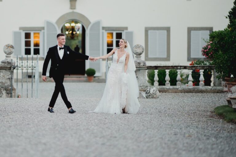 The couple walking across the gravel courtyard of a villa, Caterina Weddings