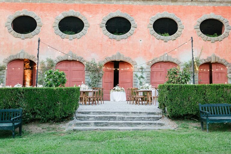Sweetheart table set before the arched red doors of a villa, Caterina Weddings