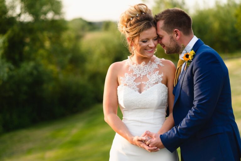 A couple in a close embrace, the bride in a fitted gown with a sheer lace halter neckline, Catherine Blades Couture