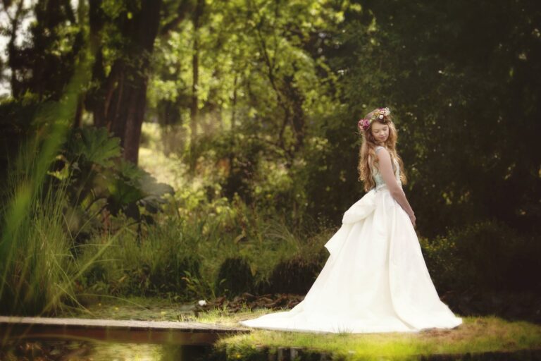 A bride in a floral crown and a gown with a fitted bodice and full skirt beside a pond, Catherine Blades Couture