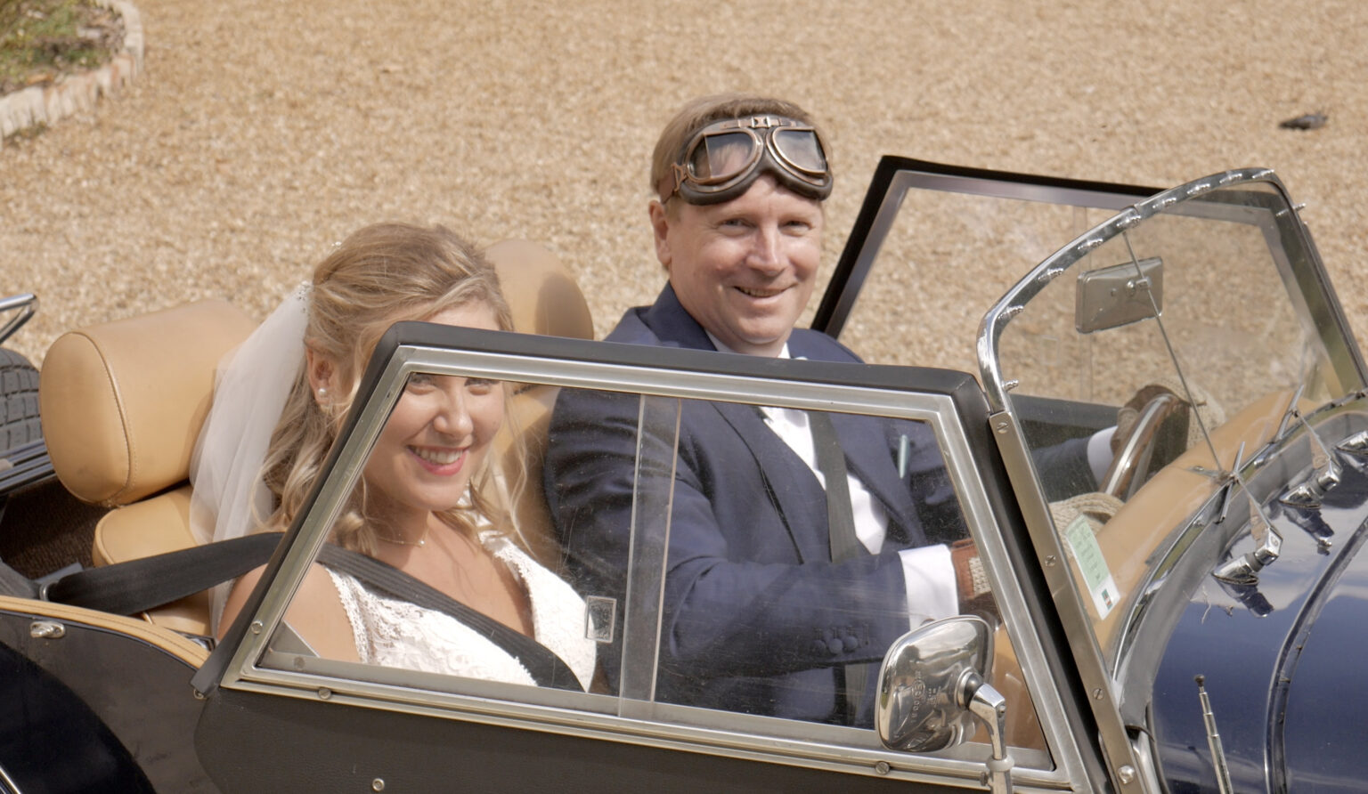 A couple arriving in a vintage open car