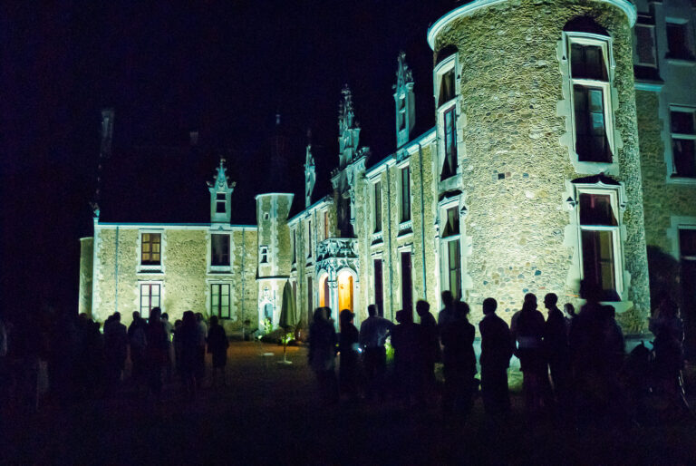 Guests gathered in front of the illuminated chateau in the evening, Château de Chéronne