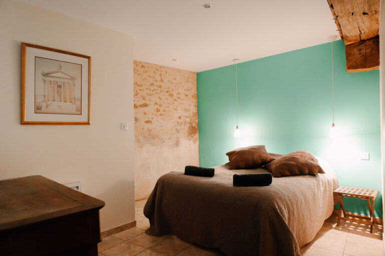 Bedroom with a green accent wall and exposed stone, Château de Chéronne