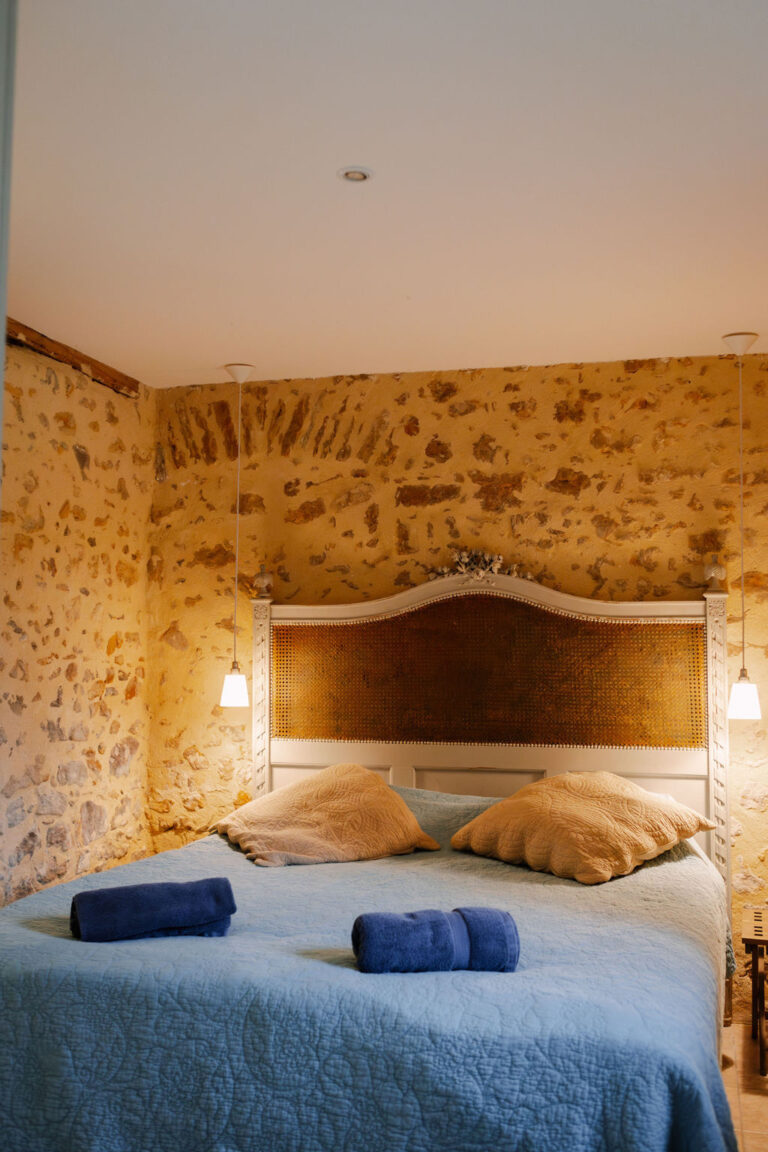 Bedroom with a blue bedspread and gold headboard, Château de Chéronne
