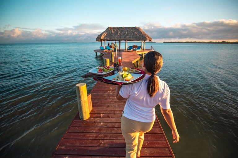 A server carrying breakfast along the pier at sunrise, Chabil Mar Resort