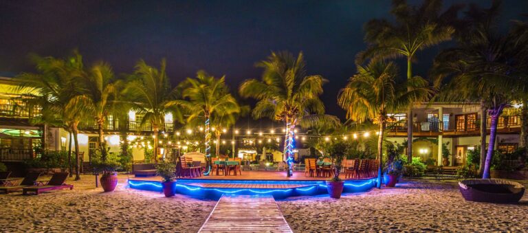 The resort beachfront lit at dusk, the infinity pool and villas glowing above the sand, Chabil Mar Resort
